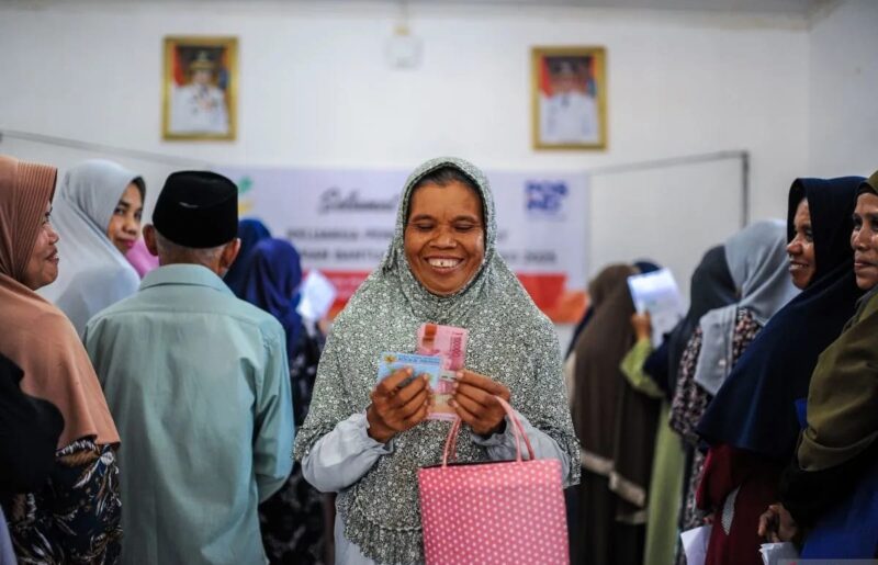 Seorang warga penerima bantuan menunjukkan uang bansos Program Keluarga Harapan (PKH) di Kantor Kecamatan Ciomas, Kabupaten, Serang, Banten, Selasa (25/2/2025).