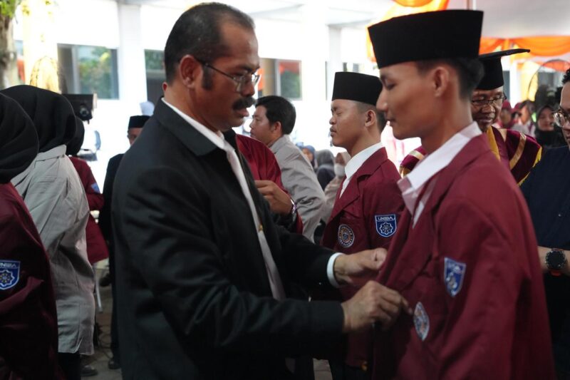 Ketua Dewan Pembina Yayasan Prof Furtasan Ali Yusuf memakaikan jas almamater kepada salah satu mahasiswa baru (maba), Rabu 24 September 2025.